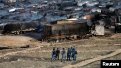 阿富汗警察站在油罐車遭焚燒後的現場