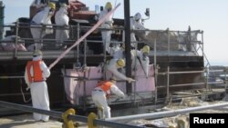 Workers are trying to remove unused nuclear fuel assemblies stored in the spent fuel pool tsunami-crippled Fukushima Daiichi Nuclear Power Plant No. 4 reactor building, July 19, 2012.