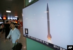 A man passes by a TV news program with file footage of a North Korean rocket launch at the Seoul Railway Station in Seoul, South Korea, Wednesday, Aug. 3, 2016.