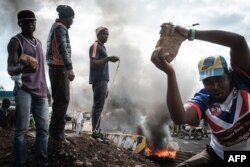 Opposition supporters hold up bricks as they block streets and burn tires during a protest in Kisumu, Kenya, on Oct. 11, 2017.