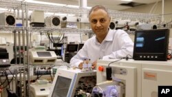 In this Aug. 10, 2015, photo, Dr. Akhilesh Pandey, a researcher at Johns Hopkins University, poses alongside a mass spectrometer in his laboratory in Baltimore.