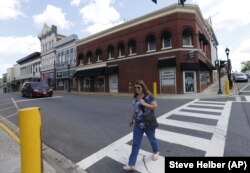 In this May 6, 2019, photo, a pedestrian crosses the street in front of the old Green's drugstore that is the site a tribute center for the Bedford Boys in Bedford, Virginia.