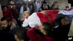 Mourners carry the body of Palestinian woman, Amal al-Taramsi, 43, who was killed by Israeli troops during Friday's protest at the Gaza Strip's border with Israel, into the family home during her funeral in Gaza City, Jan. 12, 2019. 