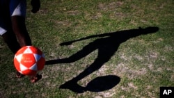 The shadow of a boy controlling a soccer ball is cast on a grassy area on the Barra de Tijuca beach while playing 'altinho' in Rio de Janeiro, Brazil, June 2, 2014. 