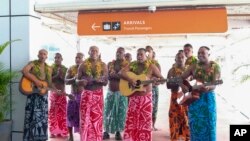Para tamu disambut dengan penampilan tradisional Fiji saat mereka tiba di bandara internasional Nadi, Fiji, 1 Desember 2021. (Bruce Rounds/Tourism Fiji via AP)
