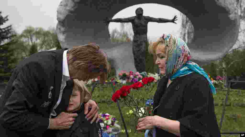 یکی از کارکنان سابق نیروگاه اتمی چرنوبیل با همسر و نوه اش در سی امین سالروز فاجعه اتمی چرنوبیل از گورستان چرنوبیل دیدار می کنند