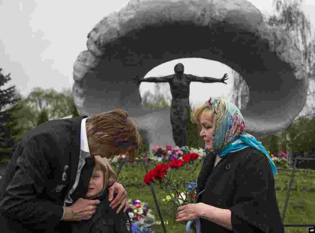 Alexander Burinin, left, former Chernobyl liquidator, his wife Olga and grandson Georgy visit Mitino Cemetery in Moscow, Russia on the 30th anniversary of the explosion at the Chernobyl nuclear plant.