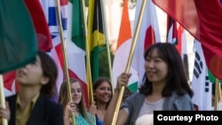 国际学生举着代表他们自己国家的国旗参加美国密苏里州立大学毕业典礼。