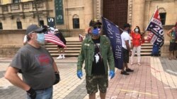 Manifestantes frente a la Torre de la Libertad de Miami exigen a las autoridades estatales medidas más severas para que la gente pueda regresar a sus trabajos lo antes posible.