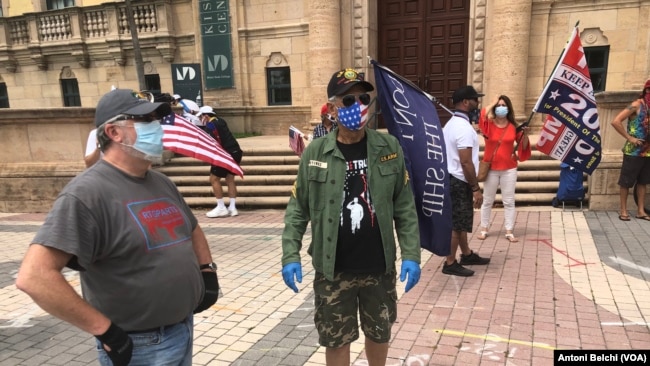 Manifestantes frente a la Torre de la Libertad de Miami exigen a las autoridades estatales medidas más severas para que la gente pueda regresar a sus trabajos lo antes posible.