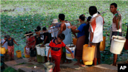 In this photo taken on April 21, 2012, local residents line up to fetch drinking water from a lake in Rangoon, Burma. (AP Photo)