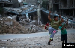 Palestinian children play near houses reportedly damaged during the Israeli offensive, in northern Gaza Strip town of Beit Hanoun, on Oct. 13, 2014.