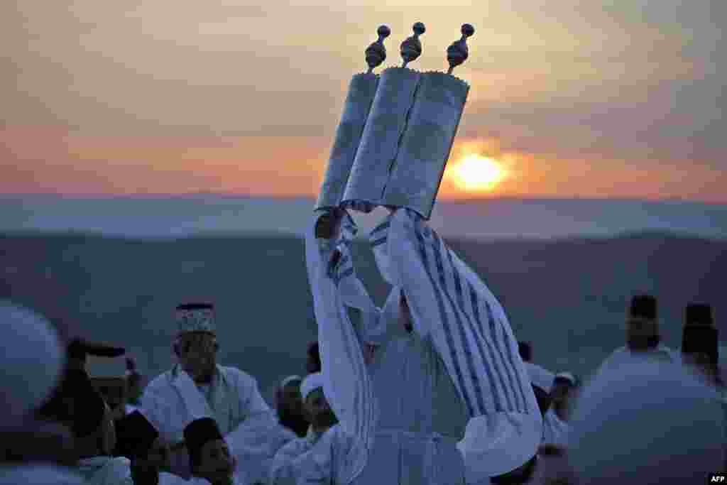 A Samaritan priest raises the Torah scroll as worshippers gather to pray at a Passover ceremony on top of Mount Gerizim near the northern West Bank city of Nablus.