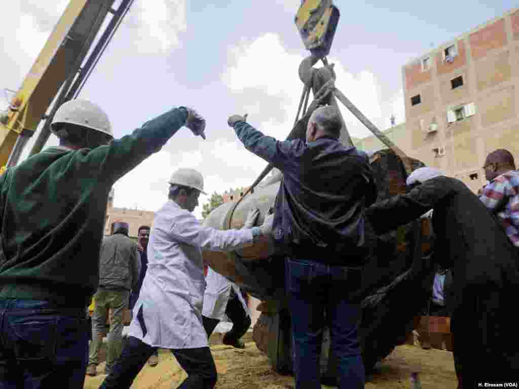 Archaeologists help landing the statue.