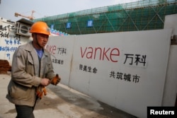 A person walks past by a gate with a sign of Vanke at a construction site in Shanghai, China, March 21, 2017.
