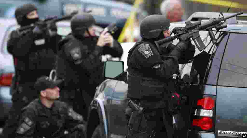 Police in tactical gear surround an apartment building while looking for a suspect in the Boston Marathon bombings in Watertown, Mass., Friday, April 19, 2013.