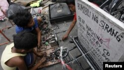 Children recover copper and other metals from discarded televisions and other electronic waste, which they exchange for money from nearby junkshops, along a road in Manila April 7, 2011. An e-waste recycling and reclamation company salvages gold and other