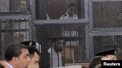 Para terdakwa di belakang jeruji besi dalam pengadilan di Mesir (18/6) atas tuduhan membunuh Mayjen Nabil Faraq.