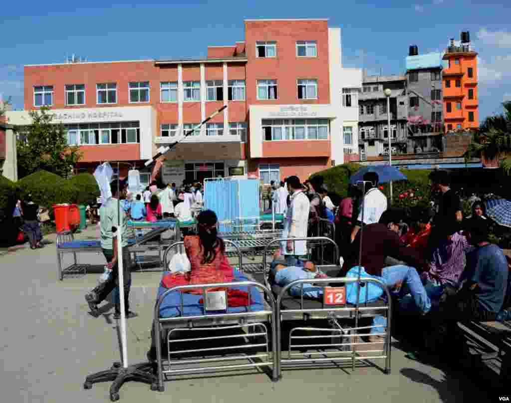 Pasien-pasien Teaching Hospital, Kathmandu, beberapa masih di atas ranjang mereka, menunggu di luar rumah sakit (12/5). (VOA/Bikas Rauniar)&nbsp;