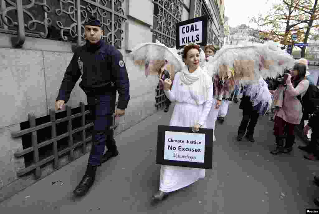 A French police officer escorts Australian environmental activists called Climate Guardian Angels during a demonstration as part of the World Climate Change Conference 2015 (COP21) in Paris.