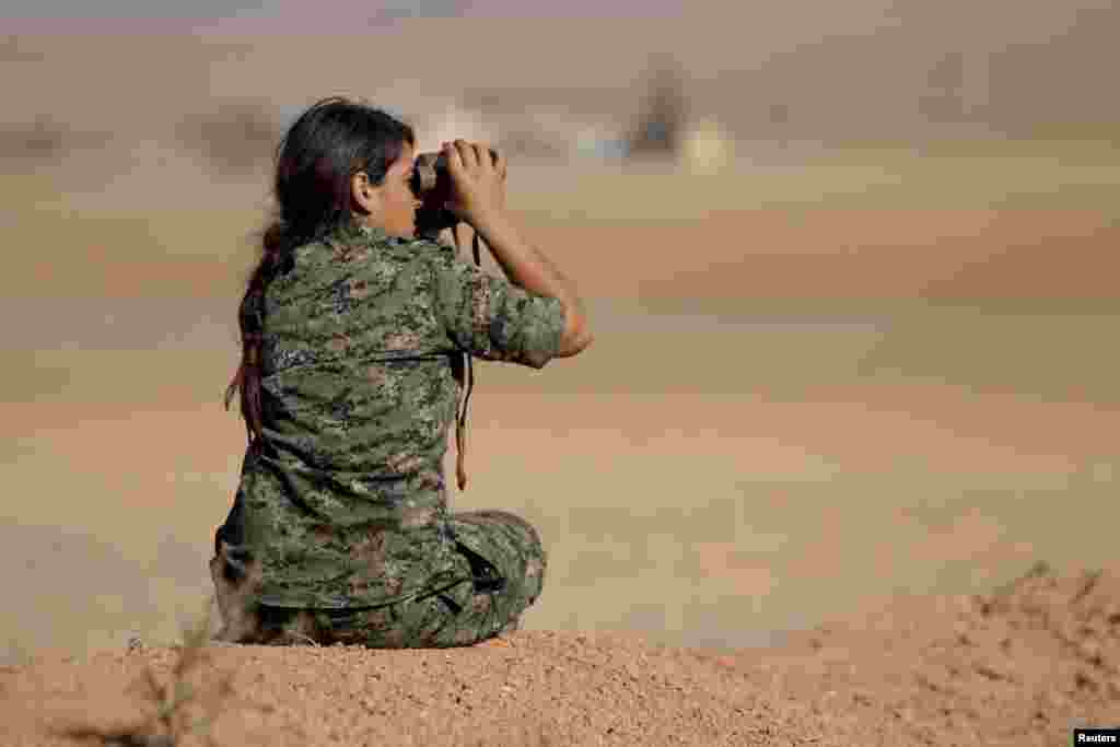 A female fighter of the Kurdish People&#39;s Protection Units (YPG) uses a pair of binoculars as she looks toward areas controlled by Islamic State fighters in the southern countryside of Ras al-Ain Sunday. 