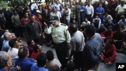 지난 8월 이란 산업부 건물 앞에서 임금 체불에 항의하며 벌어진 노동자들의 시위 중, 경찰 간부(가운데) 해산을 요구하고 있다. (자료 사진)