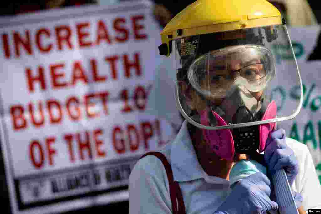 A healthcare worker joins a protest calling for better government actions during the coronavirus outbreak, as the one-year anniversary of the first COVID-19 case in the Philippines nears, outside a government hospital in Quezon City, metro Manila.