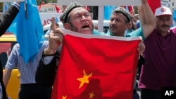 FILE - Uighurs living in Turkey and Turkish supporters, chant slogans before burning a Chinese flag, July 5, 2015. Since 2013, thousands of Uighurs, a Turkic-speaking Muslim minority from western China, have traveled to Syria to train and fight alongside al Qaida.