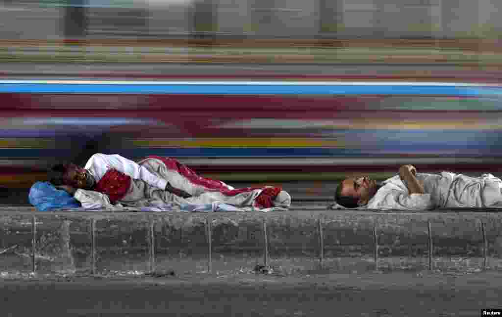 پاکستان کے شہر کراچی میں دو افراد سڑک کے کنارے سو رہے ہیں۔