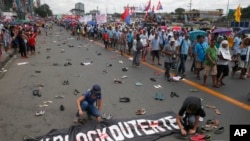 Người biểu tình rải những chiếc giầy, dép trên đường để tượng trưng cho các nạn nhân bị giết trong chiến tranh chống ma túy của TT Duterte giữa lúc nhiều người khác tiến về Hạ Viện, nơi ông Duterte đọc bài diễn văn về tình trạng quốc gia thứ nhì hôm Thứ Hai, 24/7/2017. (AP Photo/Bullit Marquez) 
