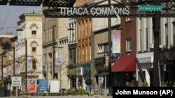 In this April 15, 2020 photo, a lone pedestrian makes their way through the Ithaca Commons in Ithaca, N.Y. Most of the almost 24,000 students at Cornell University and 6,200 more from Ithaca College effectively vanished in March when the pandemic struck. (John Munson/Cornell)