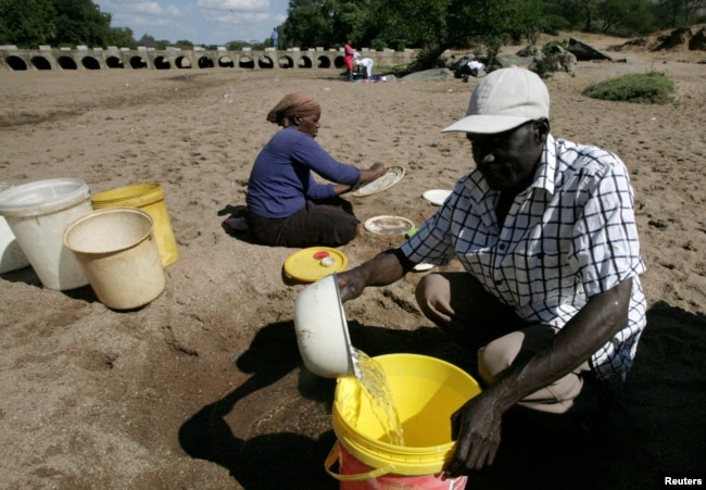 FILE - Villagers collect water from a dry riverbed in drought-hit Masvingo, Zimbabwe, June 2, 2016.