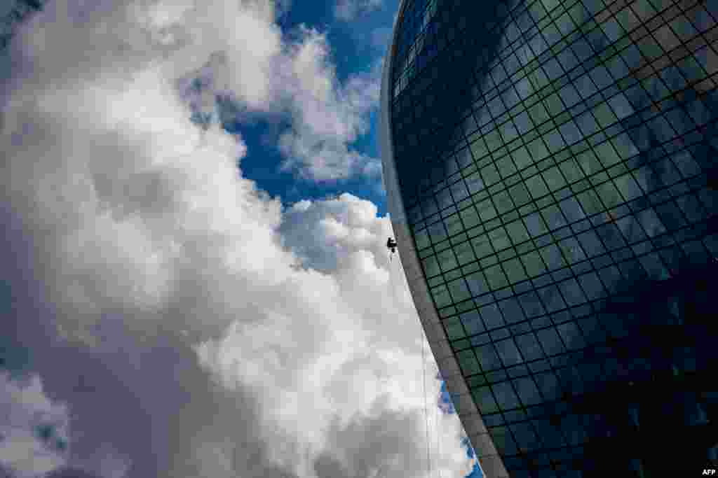 A worker cleans the windows and the front of an office building in Moscow&#39;s International Business Centre, August 23, 2021.