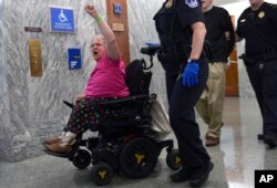 Una manifestante en silla de ruedas protesta contra la propuesta de salud republicana en el Congreso de EE.UU. mientras la policía del Capitolio, la retira de la sala donde senadores revisaban la medida. Sept. 25, 2017.