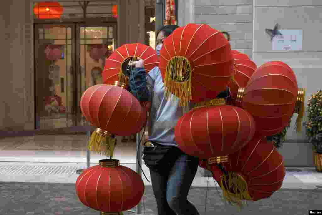 A worker wearing a face mask carries red lanterns ahead of the Lunar New Year, in Hong Kong.