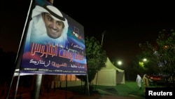 Supporters are seen walking next to a campaign banner of Osama Yousif Al-Tahoos, candidate from Third District, Kuwait City, July 26, 2013.