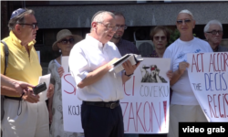 Rabin Isak Asiel čita okupljenima Toru tokom protesta članova jevrejske zajednice ispred Ministarstva pravde zbog odbijanja da se u Registar crkava i verskih zajednica upiše ime novoizabranog predsednika Jevrejske opštine Beograd, Aleksandra Saše Jinkera, u Beogradu, 23. jula 2019.