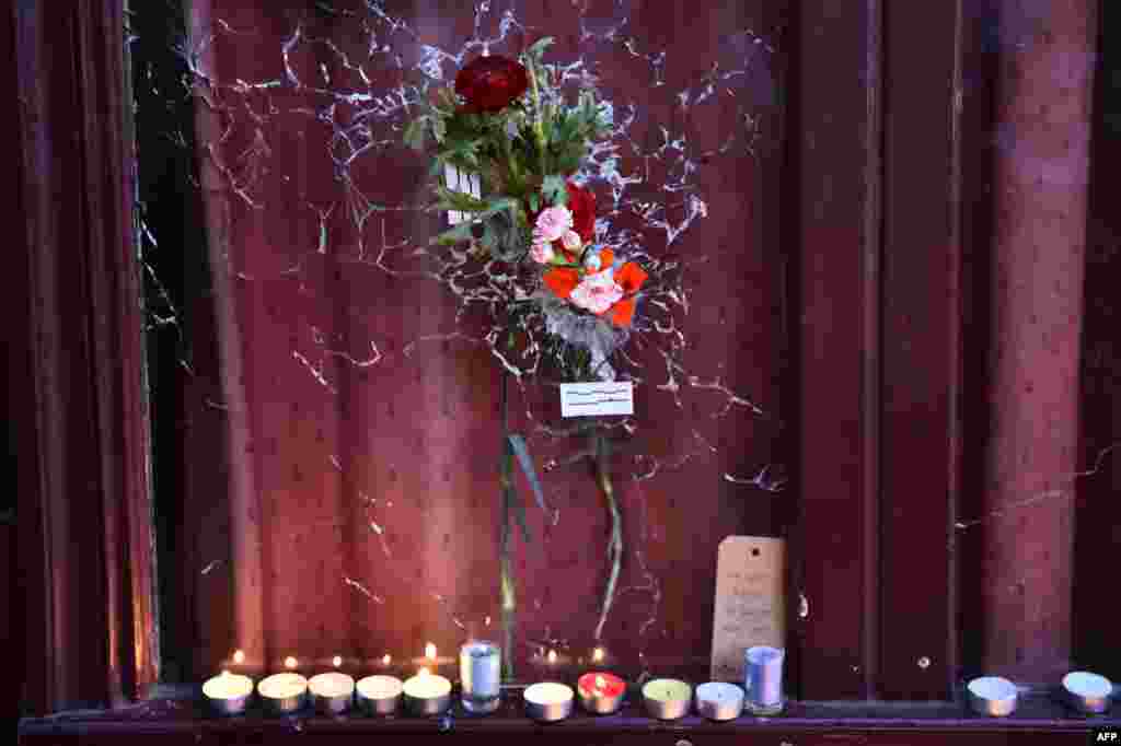 프랑스 파리에서 벌어진 연쇄 테러 공격 장소 중 한 곳인 10지구 '르 카리용' 식당의 깨진 유리창에 희생자들을 추모하는 꽃과 초가 놓여있다. 파리에서는 지난 13일 이슬람 극단주의자들의 테러 공격으로 129명이 숨졌다.