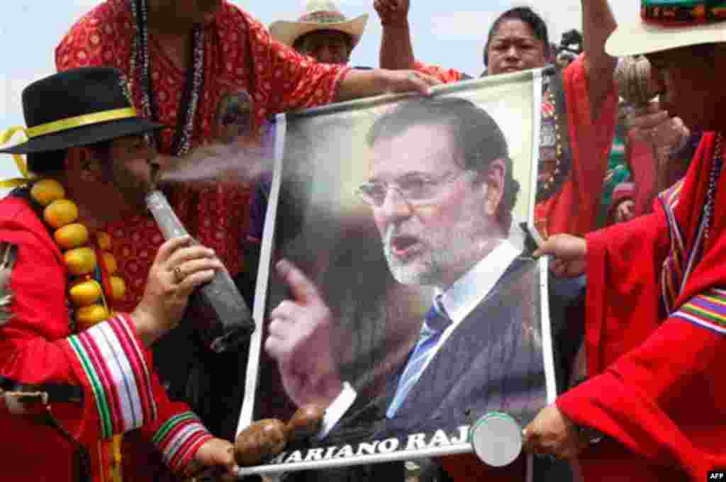 A shaman spits flowered water on a poster of Spain's Prime Minister Mariano Rajoy during a ritual for good luck in 2012 in Lima, Peru, Thursday Dec. 29, 2011. (AP Photo/Karel Navarro)