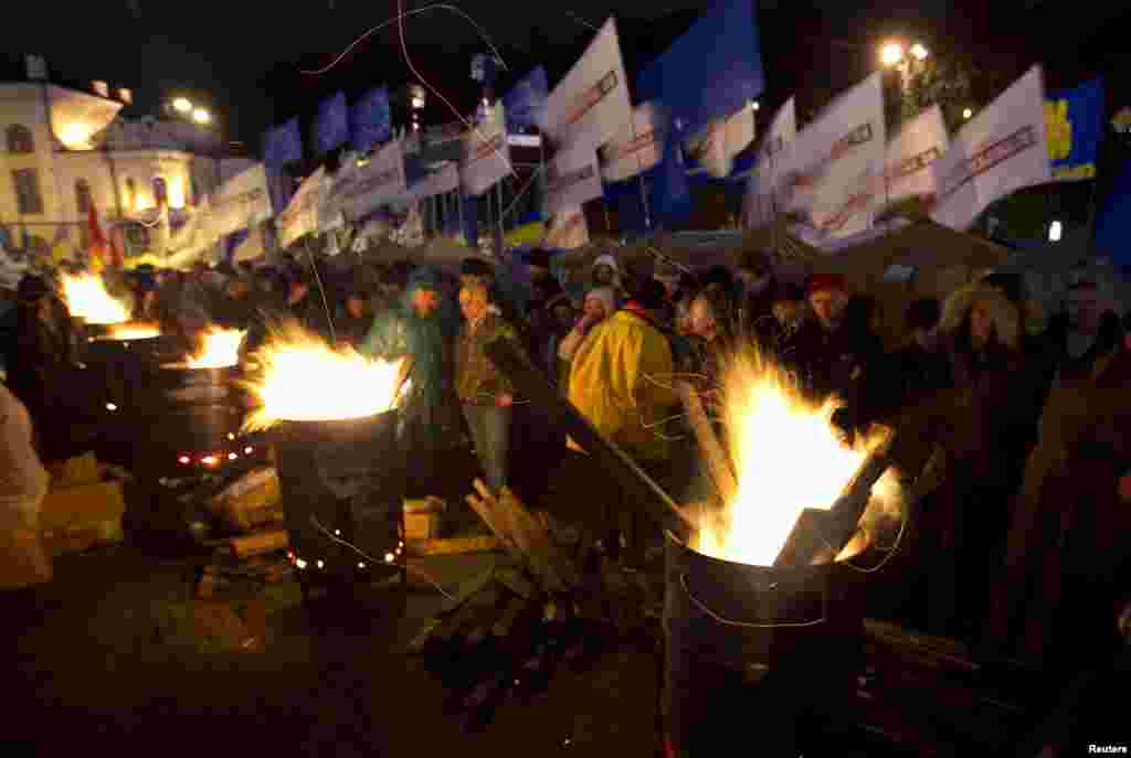 People warm themselves at fires made in steel drums after a meeting to support EU integration at European Square in Kyiv, Nov. 26, 2013. 