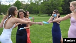 Lauren Copeland, Camille Steiger, Ruby Roberts, Micah Long and Elizabeth Toomey put on masks while posing for photographs in their prom dresses in Milton, Mass May 16, 2020. (REUTERS/Faith Ninivaggi)
