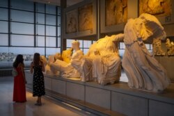 FILE - Two women visit the Athens Acropolis Museum as the museums and archaeological sites open at night for two days, on Aug. 22, 2021.