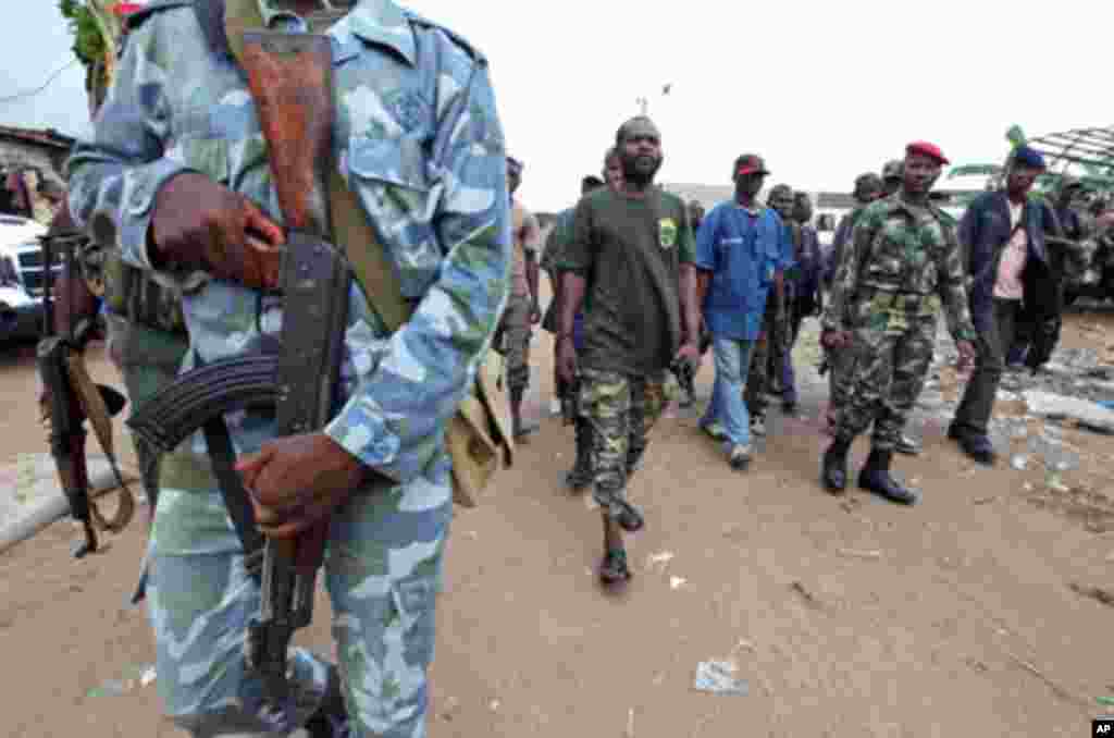 A man known as Commander Bauer, the chief of a group of pro-Ouattara fighters, walks with his men in northern Abidjan's Abobo district March 26, 2011
