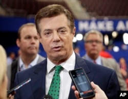 FILE - In this July 17, 2016, file photo, then-Trump Campaign Chairman Paul Manafort talks to reporters on the floor of the Republican National Convention at Quicken Loans Arena in Cleveland as Rick Gates listens at back left.