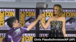 Sutradara Taika Waititi menyerahkan palu Thor kepada Natalie Portman saat diumumkannya film "Thor Love And Thunder" di acara panel Marvel Studios di Comic-Con International di San Diego, California, 20 Juli 2019 (dok: Chris Pizzello/Invision/AP)