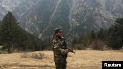 FILE - An Afghan security force personnel keeps watch near his check post in Parun, capital of Nuristan province, Afghanistan.