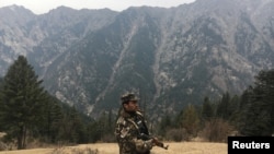 FILE - An Afghan security force personnel keeps watch near his check post in Parun, capital of Nuristan province, Afghanistan.
