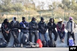 FILE - Young migrants wait to board a bus leaving for a reception center in Calais, following a massive operation to clear the "Jungle" migrant camp, Oct. 28, 2016.