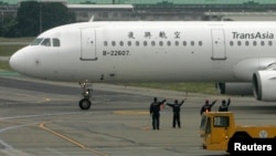 Ground crew members wave to passengers on board the TransAsia Airways airplane which is the first cross-strait flight of the day from Taiwan to Shanghai, China, at the Taipei Songshan Airport in this 2008 file photo. (REUTERS/Pichi Chuang )