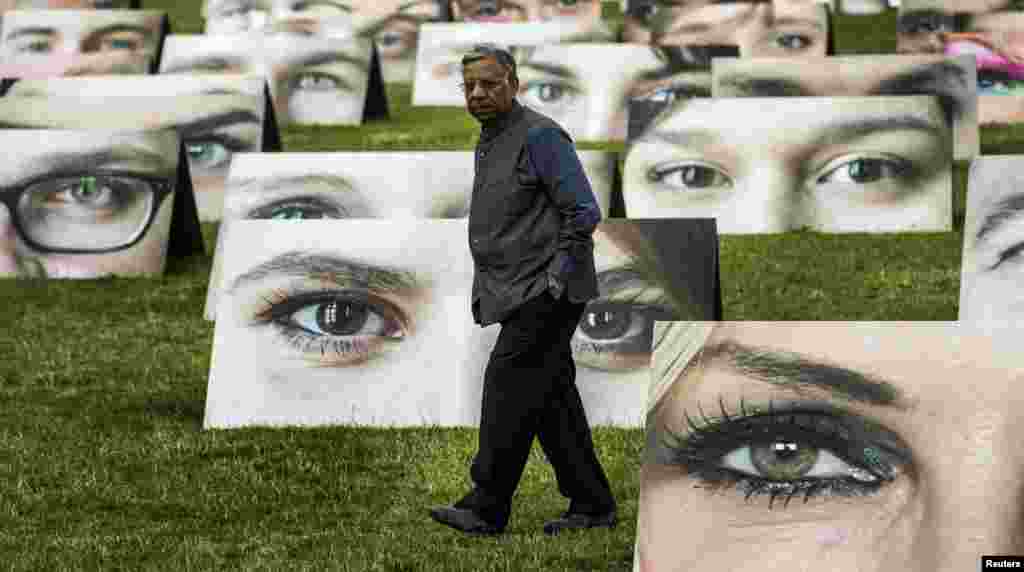 A man walks amidst cardboard displays that are part of an installation by One.org in Berlin. One.org set up 140 pictures with pairs of eyes trained at the Reichstag, the seat of Germany&#39;s lower house of parliament, to draw attention to the plight of the world&#39;s poor and symbolize the close attention people pay to the government&#39;s international development policies.&nbsp; 